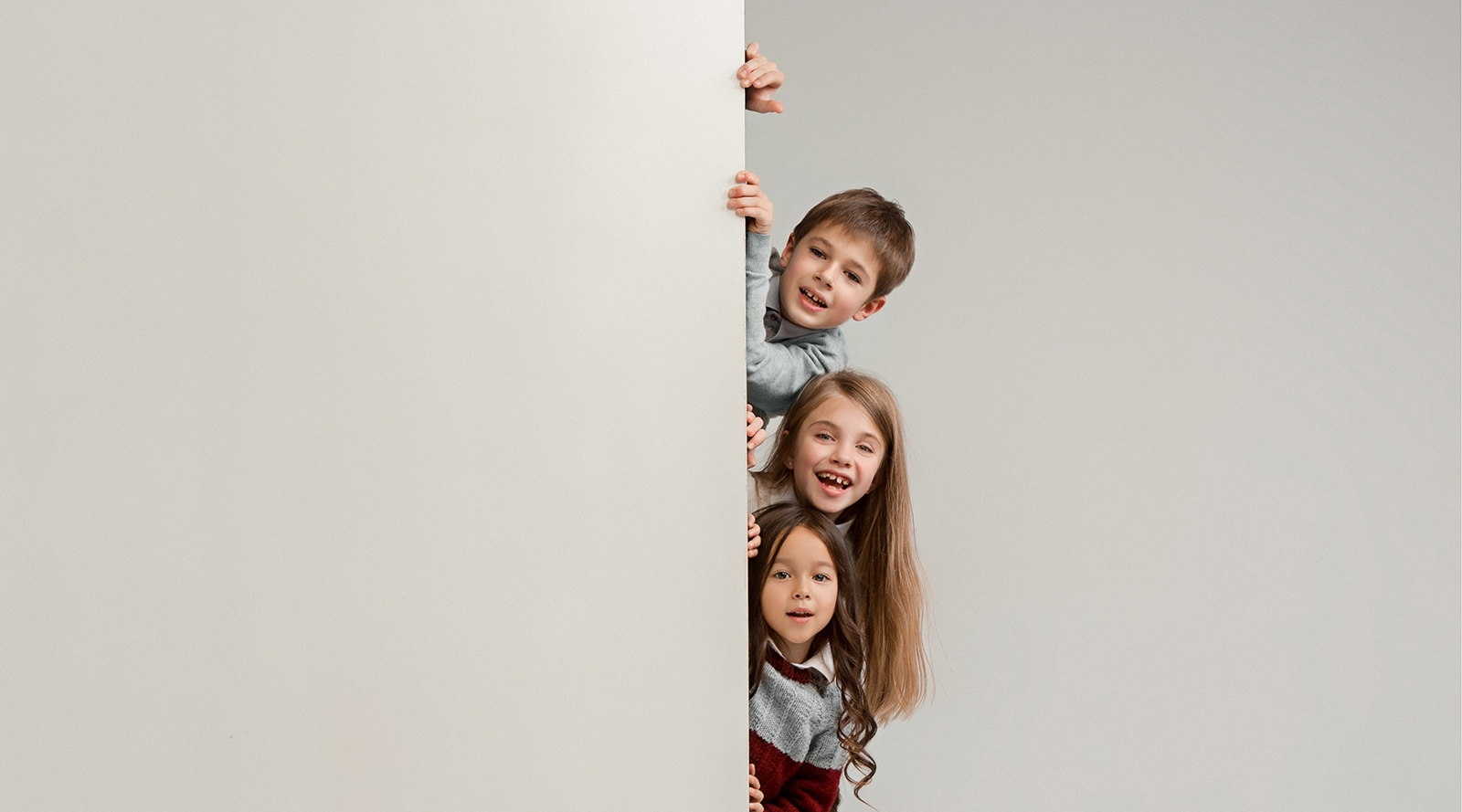children hiding behind wall